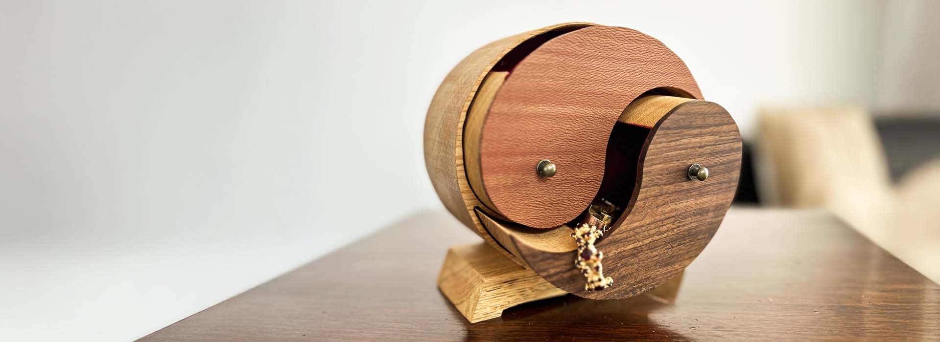 Ein rundes Schmuckkästchen aus Holz mit 2 Schubladen in unterschiedlichen Hölzern und in Form von Yin und Yang